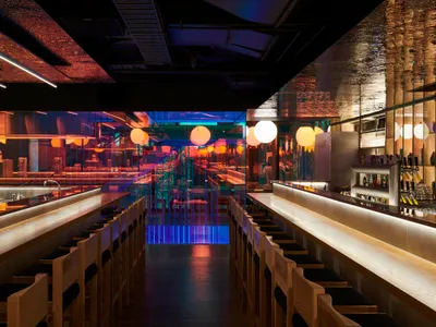 Modern minimalist restaurant with wooden seating, glass walls, and neon lights.
