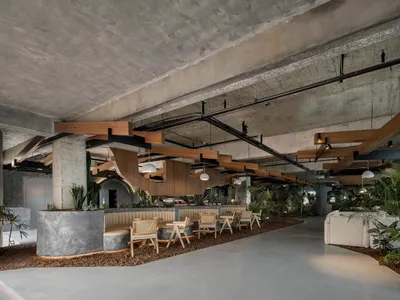 現代工業風餐廳，混凝土天花板、木質結構搭配綠色植物裝飾。