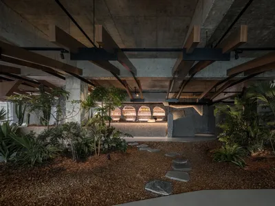 Industrial-style restaurant interior with concrete walls, wooden beams, and stone flooring.