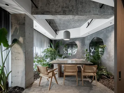 Concrete-walled industrial restaurant interior with plants and natural light.