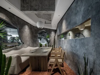 現代簡約餐廳室內，鋪設混凝土地板，搭配木質家具與綠色植栽。
