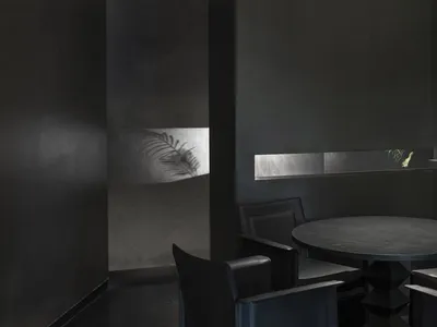 A modern black metal restaurant interior with a round table, chairs, and metallic accents.