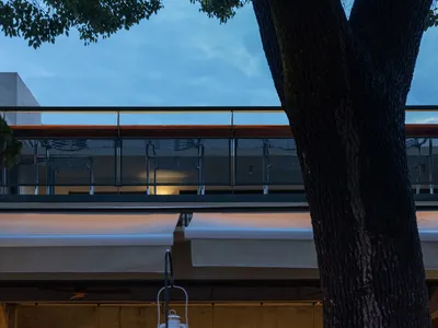 Industrial-style restaurant bar with concrete walls and a balcony overhang.