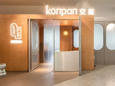 Modern minimalist restaurant entrance with glass doors and wooden paneling.