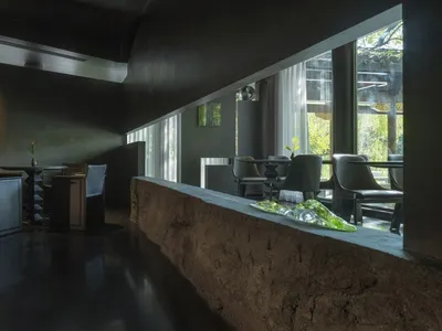 Modern restaurant interior with black concrete, industrial fixtures, and minimalist design.