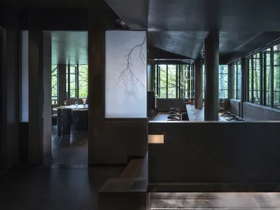 A modern minimalist restaurant lounge featuring black materials and concrete walls