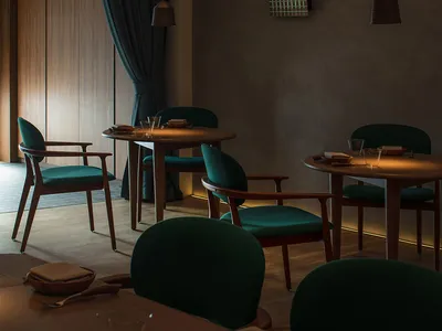 A modern restaurant interior with wooden furniture and green upholstered chairs.