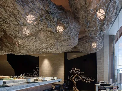 Modern restaurant interior with textured paper ceiling and tree-like structure.