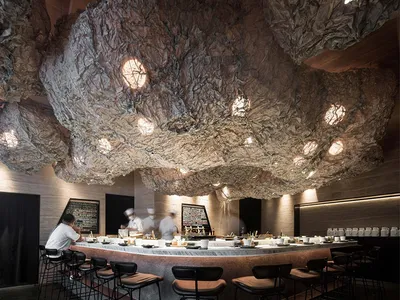 Interior of a modern, industrial-style restaurant featuring concrete and metal materials.