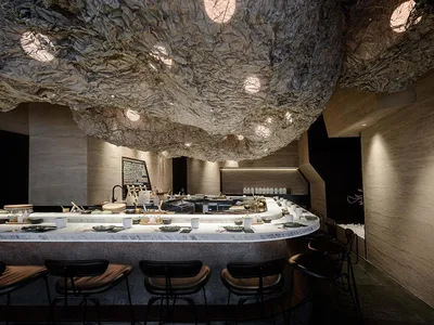 A modern restaurant bar counter with a textured fabric ceiling