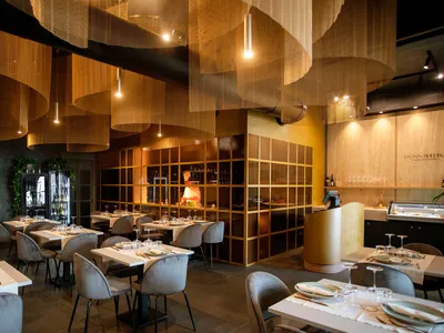 Modern restaurant interior with metallic textures and glass partitions.