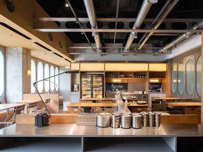 A modern restaurant interior featuring wooden tables, metallic decor, and glass elements.