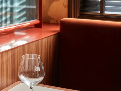 現代工業風餐廳卡座，搭配棕色木質桌椅、玻璃紅酒杯、置有筷子與湯匙的餐盤。