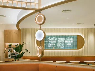 現代工業風餐廳室內，搭配木質元素，並有寫著「Let’s yum cha」的招牌。