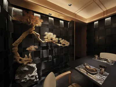 A sleek, metallic and black restaurant interior with a bonsai tree, minimalist table setting, and modern design elements.