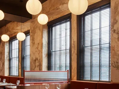 Modern cafe interior with wooden tables, velvet seating, and spherical pendant lights.