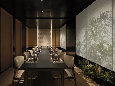 A sleek, modern dining room features a long, black dining table surrounded by plush, cream-colored chairs under a dark, minim