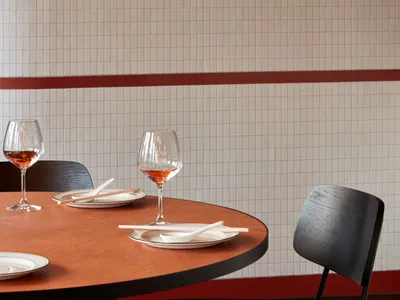 A modern dining area featuring square wooden tables and ceramic tiles with wood flooring.