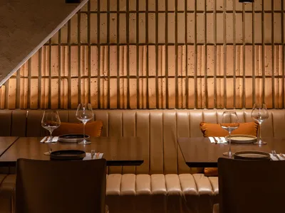A modern restaurant interior with brown leather seating and a warm, cozy atmosphere.