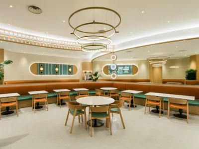 Modern restaurant interior featuring orange fabric seating and wooden furniture.