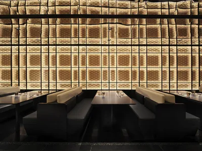 Modern restaurant interior with textured paneled walls and matte black furniture.