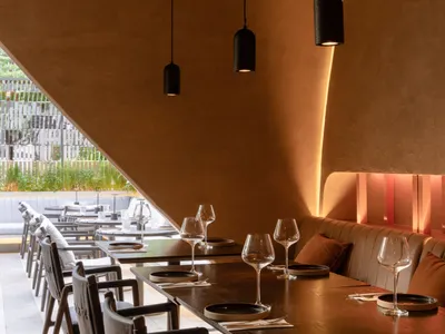 A modern restaurant interior with wooden tables, chairs, and walls.