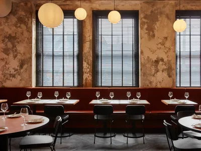 A modern restaurant interior with red leather seating and round tables.
