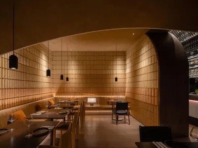 Modern wooden restaurant interior with tables, chairs, and pendant lights.