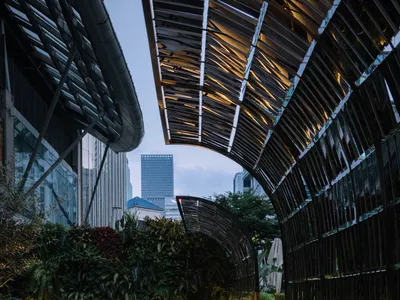 A modern restaurant with metal structures and greenery outdoors.