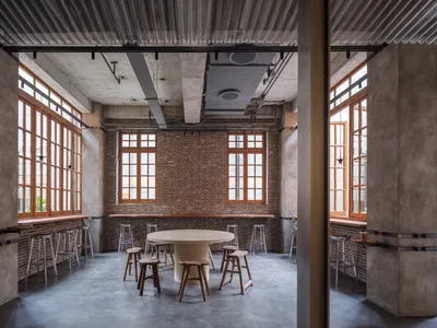 Industrial design restaurant interior with brick walls, concrete flooring, and large windows.