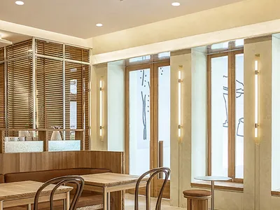 Modern cafe restaurant interior with wood furniture, glass walls, and marble floor.