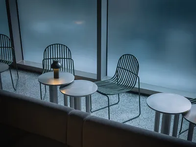 A modern restaurant interior with metal furniture and round tables.