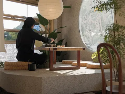 A person sitting at a wooden table in a cafe with concrete surroundings.