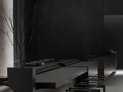 A dark, minimalist restaurant interior with black bar stools, concrete floor, and metallic elements