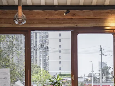 A cozy cafe interior featuring wooden furniture and a window view of urban buildings.