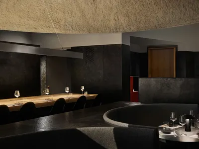 A minimalist restaurant interior with concrete walls and a sleek, modern design.