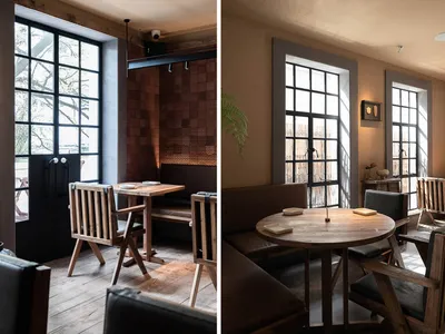 Modern restaurant interior with wooden tables and chairs, leather seating, and metal accents.