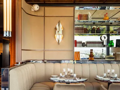 A modern restaurant seating area with upholstered seating, marble tables, and wooden walls.