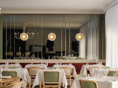 Modern restaurant interior with white tables, chairs, and pendant lights.