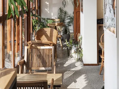 Industrial-style restaurant interior with wooden furniture and plants.