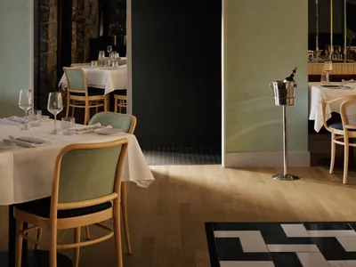A modern restaurant interior with sleek, contemporary design elements, highlighted by a green wall with two arched doorways l