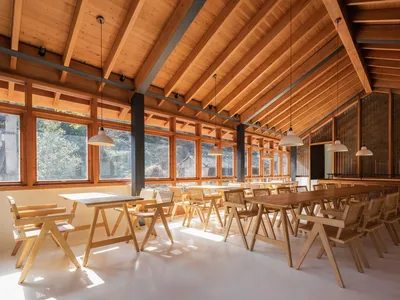 寬敞的餐廳內部，擺放木製餐桌與餐椅，並有高挑的木樑天花板。