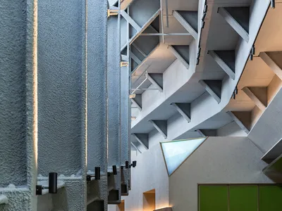 A spacious modern restaurant interior with concrete walls, stone floors, and sleek furniture.