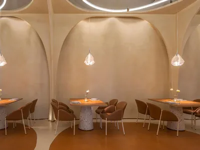 Modern restaurant dining area with terrazzo tables and chairs, minimalistic design style, curved archways, and minimal lighti
