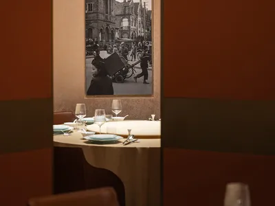 Restaurant interior with brown leather seating and a framed photograph of an urban scene.