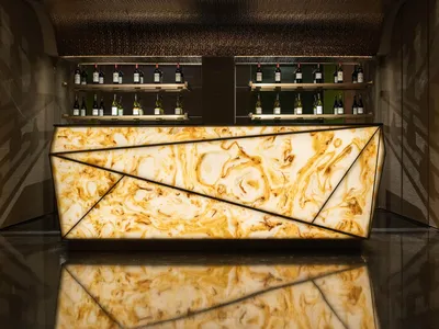A modern illuminated bar counter with marble glass design.