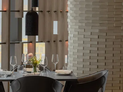 Modern restaurant interior with black chairs, white walls, and wooden accents