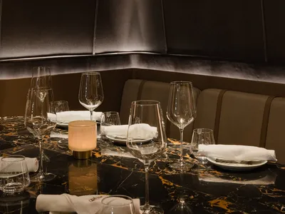 A luxury restaurant table setting with a modern design, featuring marble surfaces and elegant glassware.