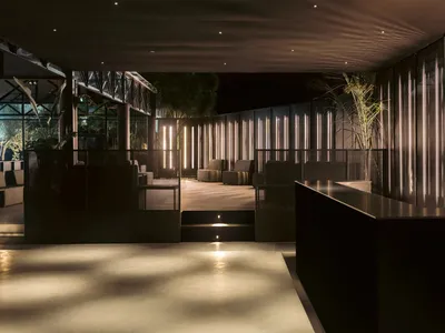 Industrial minimalist lounge area with concrete flooring, metal panels, and green plants