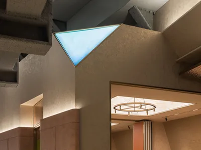 Modern restaurant dining room with concrete columns, exposed beams, and a circular light fixture